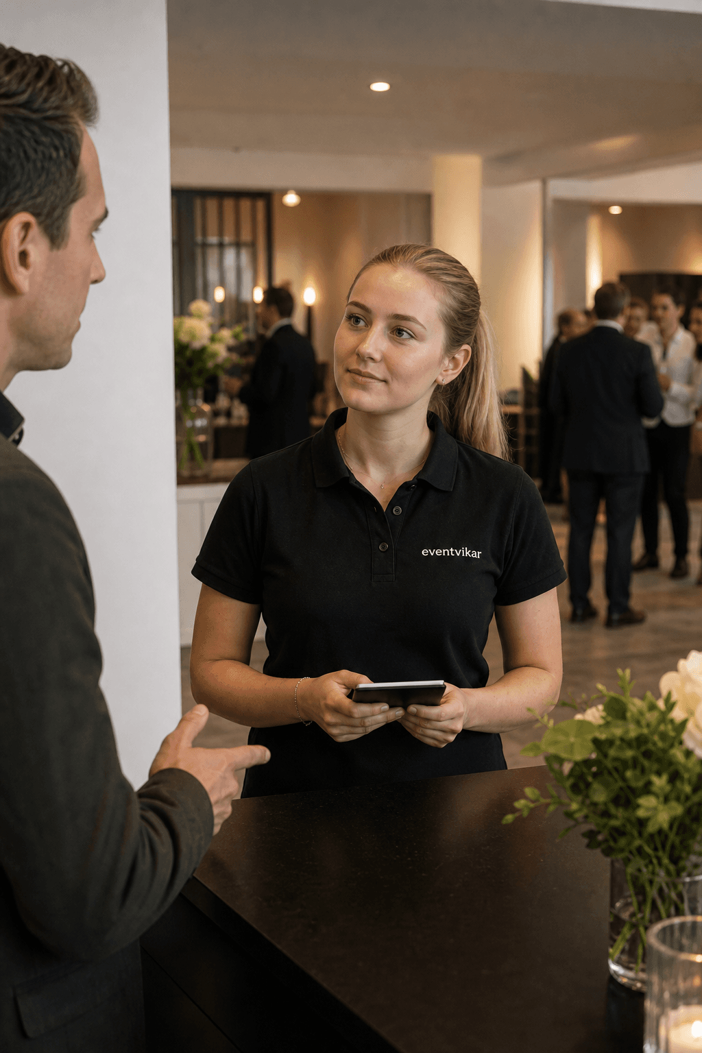 Eventvikar medarbejder taler med venue manager ved eventdesk