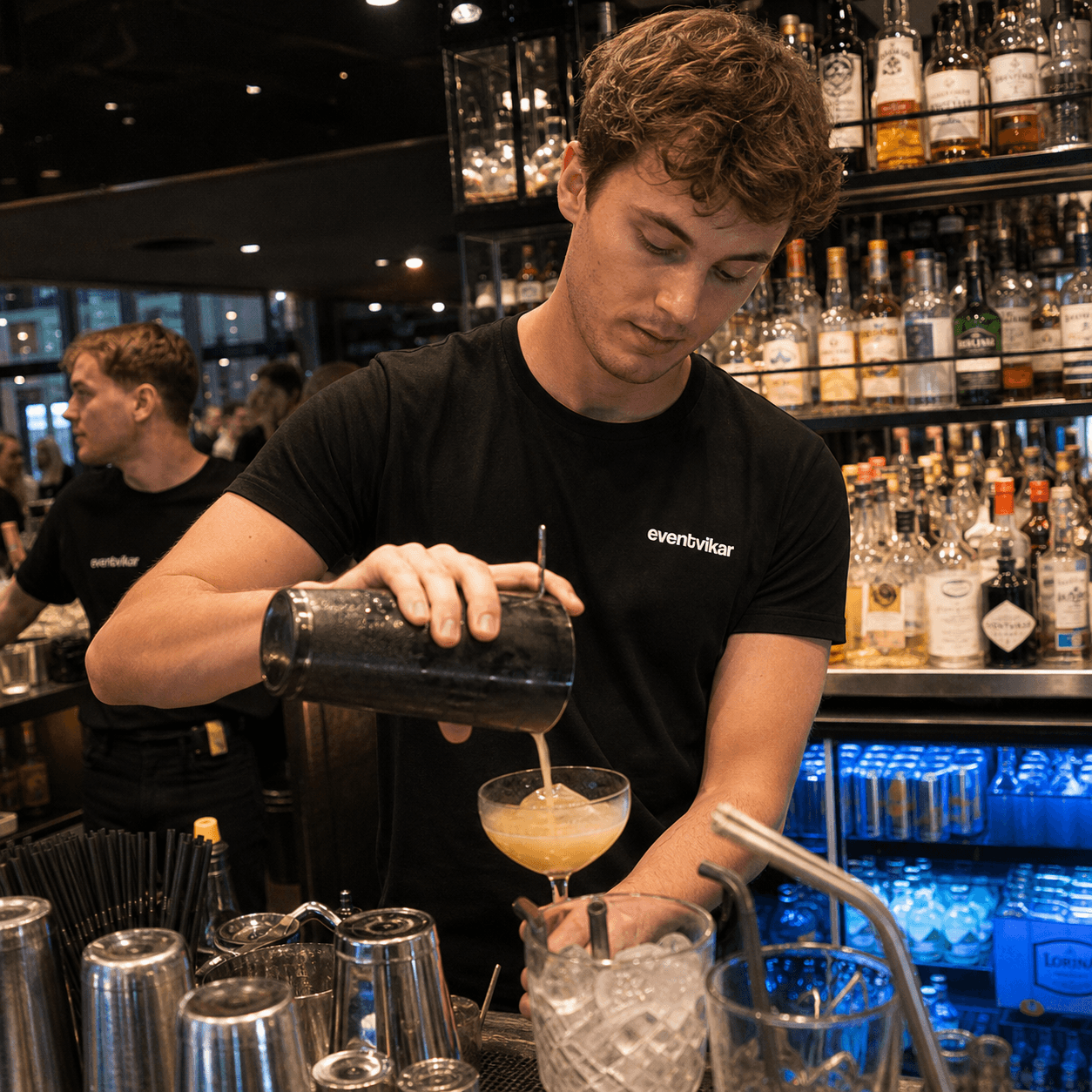 Eventvikar bartender laver drinks ved en travl bar